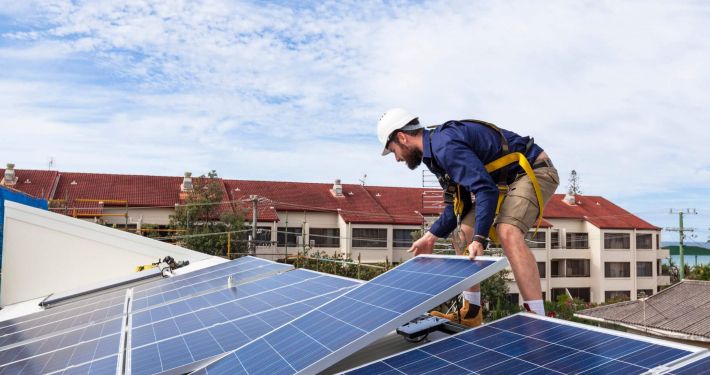 Techniker bei der Installation einer Solaranlage auf einem Hausdach zur Förderung der Solarenergie-Nutzung