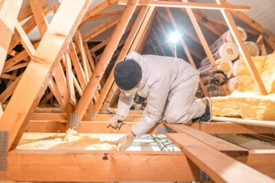 Handwerker verlegt Dämmwolle im Neubau Arbeiter installiert Dämmwolle auf Dachboden für verbesserte Energieeffizienz