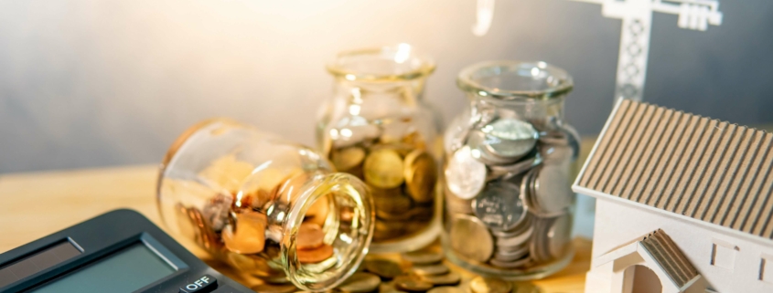 Symbolisches Geld neben einem Taschenrechner und modernen, energieeffizienten Gebäude