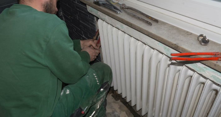 Handwerker bei der Entfernung eines alten Heizkörpers, symbolisch für den Anstieg der Sanierungsbereitschaft in Deutschland