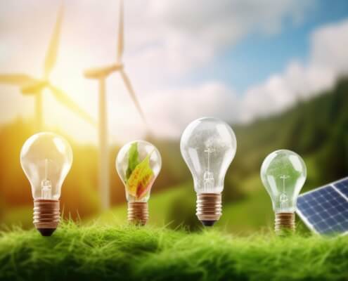 Glühbirnen auf Gras vor Windrädern, Visualisierung der Energieeffizienzziele des deutschen EnEfG