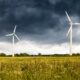 Windturbinen in ländlicher Landschaft unter stürmischem Himmel – Notwendigkeit des Ausbaus erneuerbarer Energiequellen laut Prognos AG