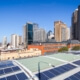Städtische Solarenergie auf Dächern mit Blick auf Großstadtsilhouette, im Einklang mit Klimazielen