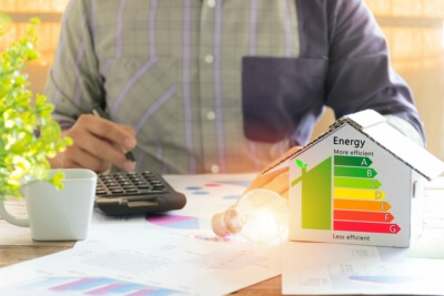 Ein Energieberater mit Taschenrechner und Energieeffizienz-Diagramm analysiert die Energiedaten eines Wohngebäudes