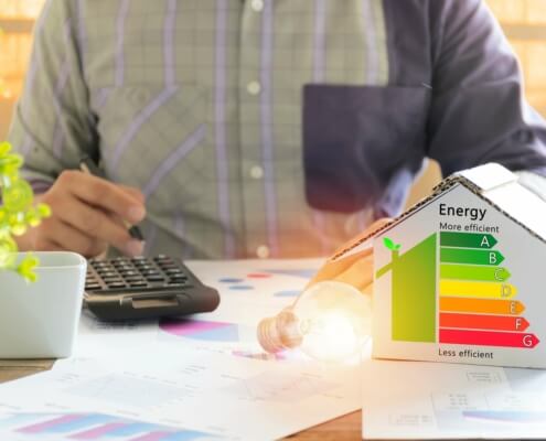 Ein Energieberater mit Taschenrechner und Energieeffizienz-Diagramm analysiert die Energiedaten eines Wohngebäudes