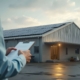 Energieberater mit Klemmbrett vor Gewerbegebäude mit Photovoltaikanlage bei Tageslicht