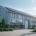 Modernes Industriegebäude mit Solarpanels auf dem Dach, umgeben von Grünanlagen, als Beispiel für energieeffiziente Unternehmensmodernisierung