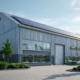 Modernes Industriegebäude mit Solarpanels auf dem Dach, umgeben von Grünanlagen, als Beispiel für energieeffiziente Unternehmensmodernisierung
