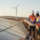 Zwei Ingenieure mit Bauplänen an einer Solaranlage vor Windrädern als Symbol für Afrikas Energiewende und EU-Investitionen