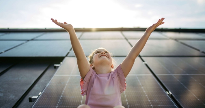 Lächelndes Kind vor Solarpanels steht symbolisch für energieeffiziente Sanierung durch Energiespar-Contracting