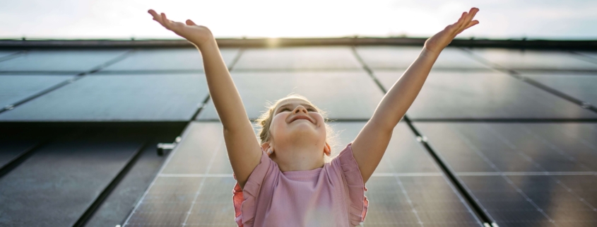 Lächelndes Kind vor Solarpanels steht symbolisch für energieeffiziente Sanierung durch Energiespar-Contracting