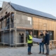Energieberaterin bespricht energetische Sanierung eines Einfamilienhauses mit Photovoltaik und Fassadendämmung auf der Baustelle