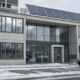 Modernes Gewerbegebäude mit Solarkollektoren und Wärmepumpe auf dem Dach im Winter – Beispiel für Heizungsmodernisierung gemäß 65-Prozent-Regel