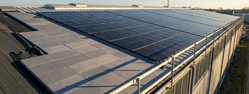 Detailaufnahme einer Hallensanierung mit Übergang von neuen Dämmplatten zu einer installierten Photovoltaik-Anlage bei Sonnenuntergang.