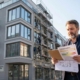 Energieberater prüft Modernisierungsunterlagen vor einem sanierten Mehrfamilienhaus mit Gerüst in einer deutschen Großstadt im Kontext der Mietrechtsreform 2026