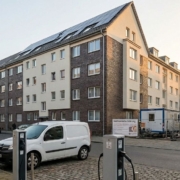 Geothermie-Bohrung neben modernisiertem Mehrfamilienhaus mit Photovoltaik und öffentlicher E-Ladestation in Nordrhein-Westfalen
