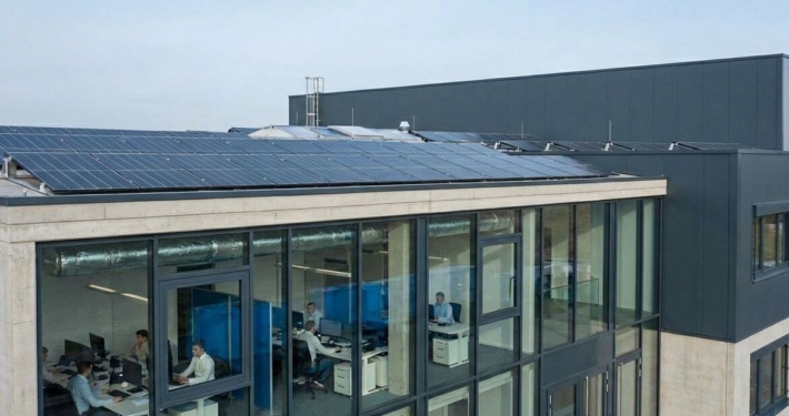 Gewerbegebäude mit Photovoltaikanlage auf dem Dach und modernen Büroarbeitsplätzen als Beispiel für Energiewende im Mittelstand