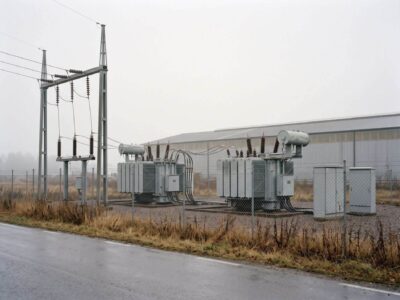 Umspannwerk mit zwei Transformatoren und Freileitung am Rand eines Gewerbegebiets bei bedecktem Herbstwetter