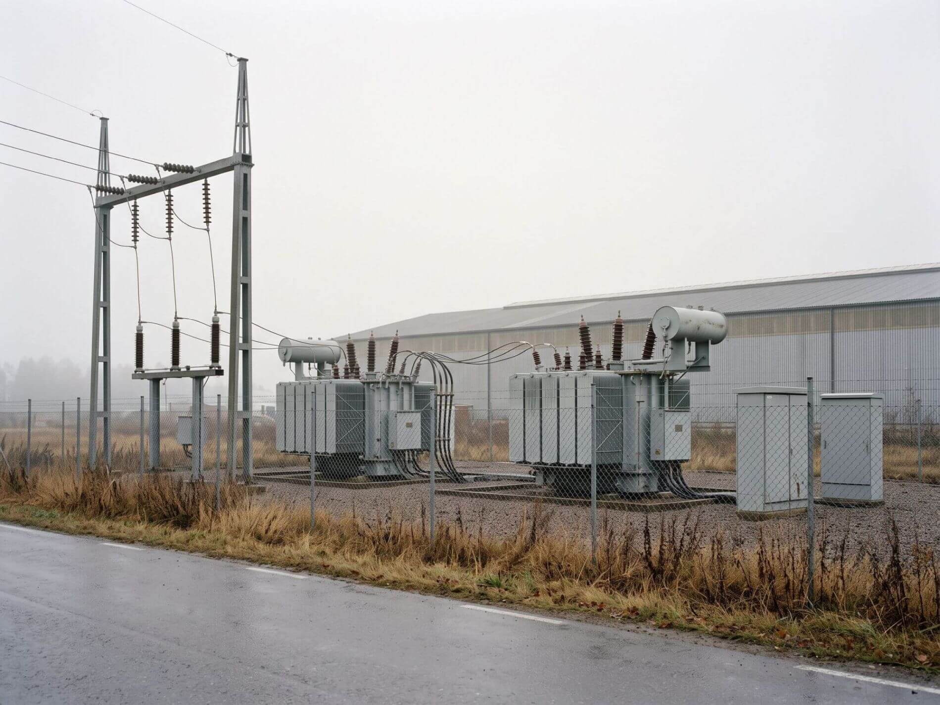 Umspannwerk mit zwei Transformatoren und Freileitung am Rand eines Gewerbegebiets bei bedecktem Herbstwetter