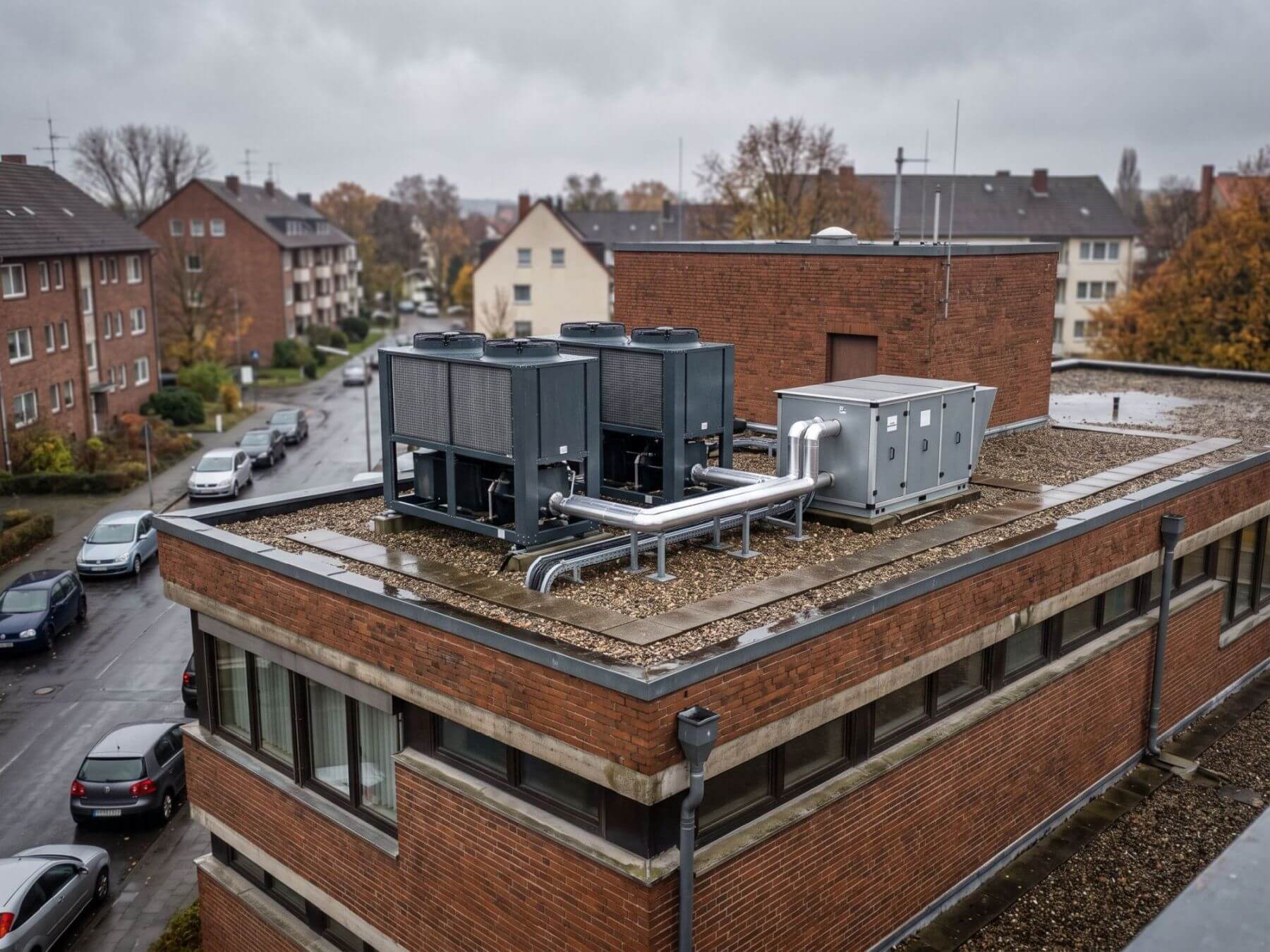 Flachdach eines kommunalen Verwaltungs- und Sportgebäudes mit Rückkühlern und Lüftungsgeräten bei bedecktem Himmel