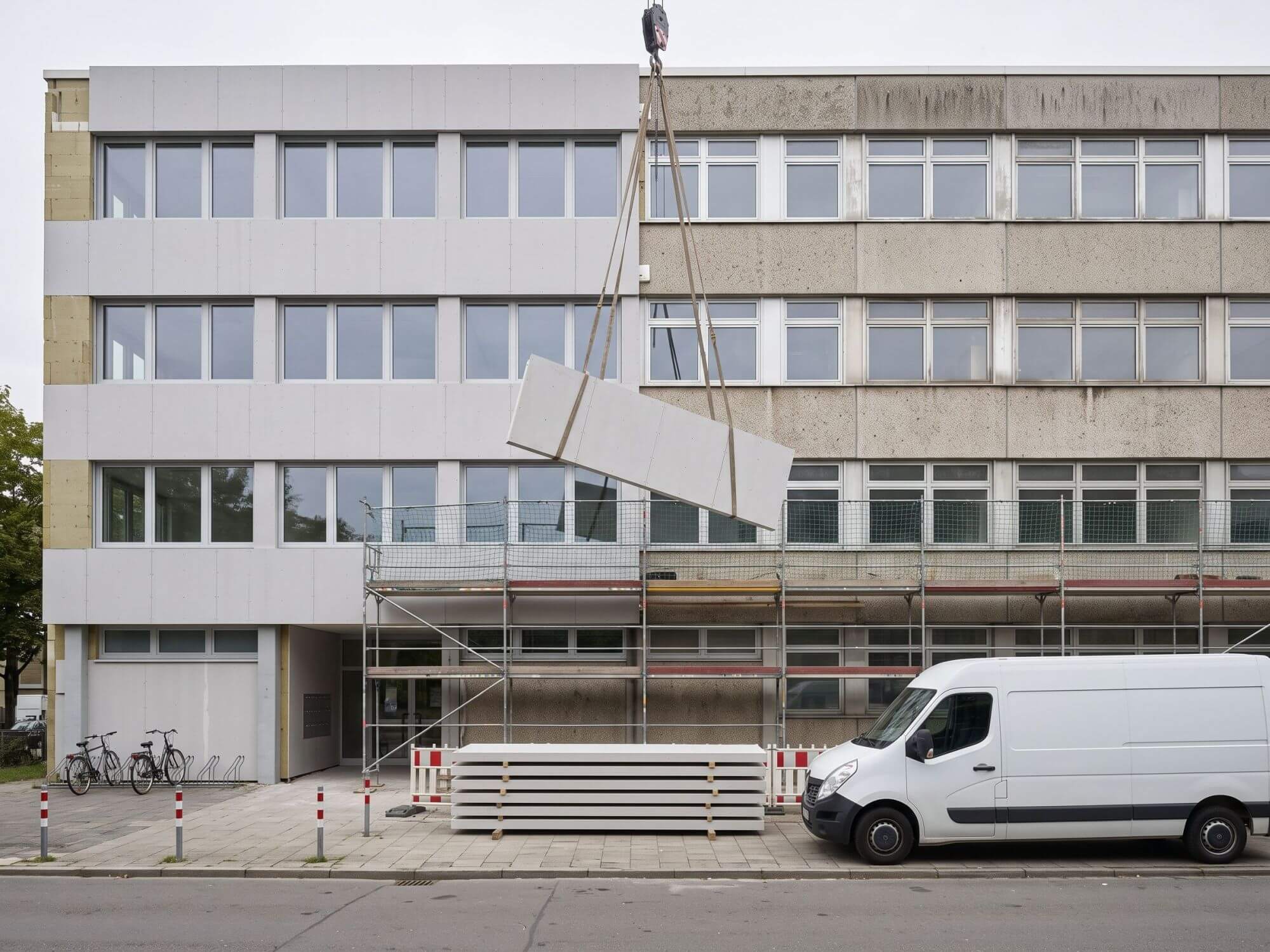 Vorgefertigtes Fassadenelement wird am Kran an die Fassade eines Nichtwohngebäudes gesetzt