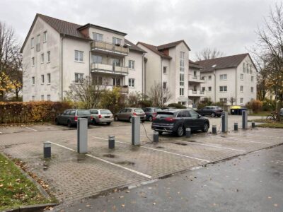 Stellplätze einer Wohnanlage mit drei Ladesäulen und Anschlusssockeln für weitere Ladepunkte