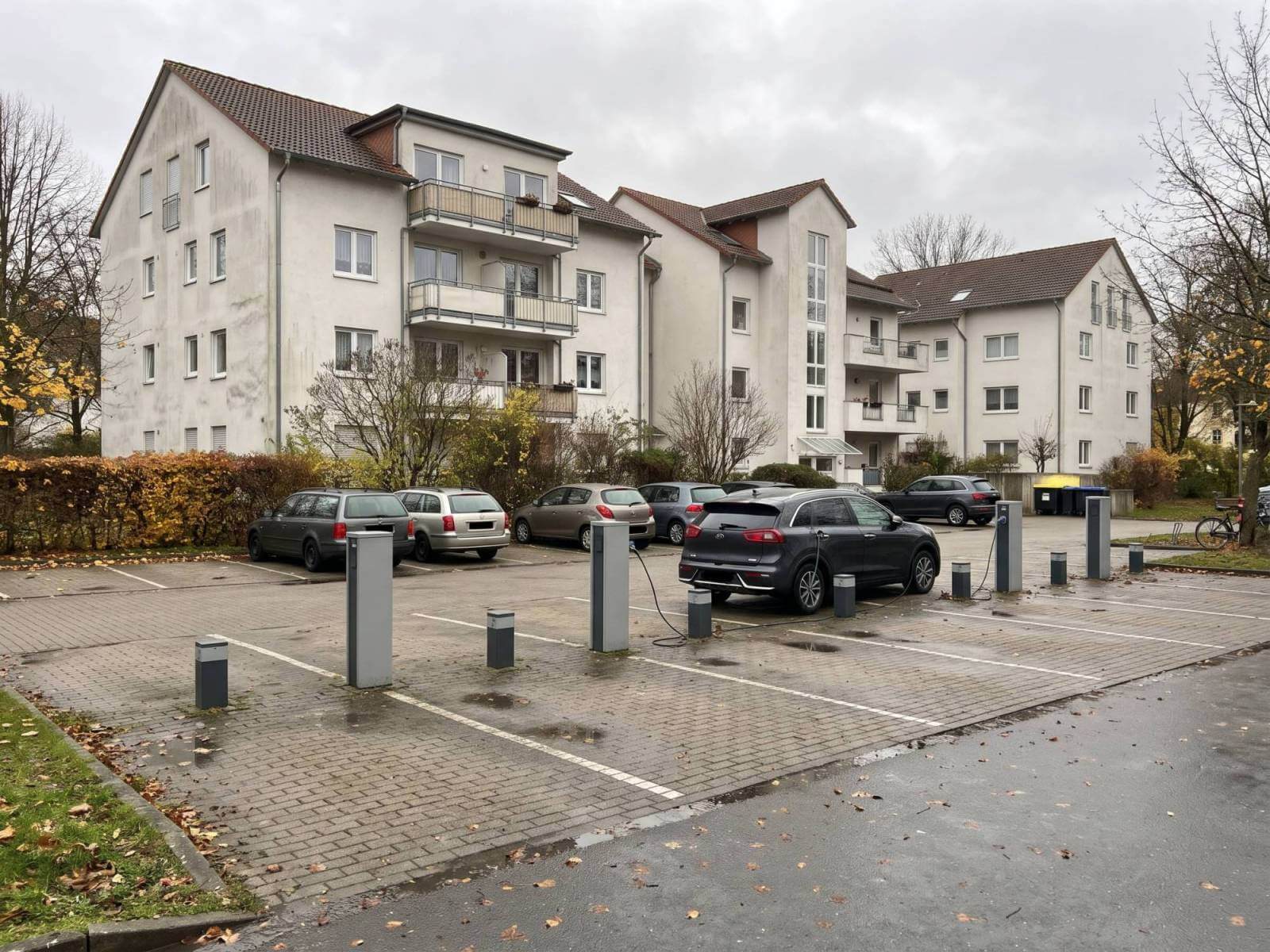 Stellplätze einer Wohnanlage mit drei Ladesäulen und Anschlusssockeln für weitere Ladepunkte