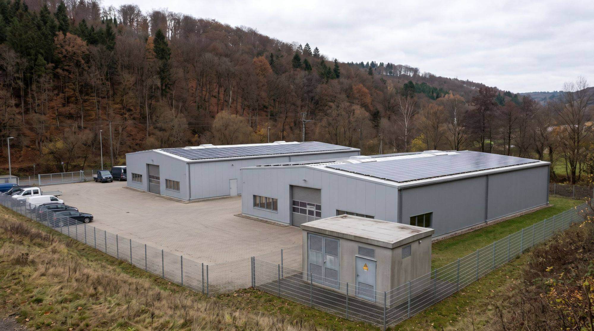 Gewerbegebiet am Rand eines Thüringer Mittelgebirgstals mit Hallen, Photovoltaik und Umspannstation