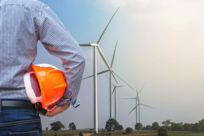 Industriemitarbeiter vor Windrädern - Symbol für Klimaschutzinvestitionen und grüne Jobs in der deutschen Industrie – Cornelius Ober GmbH