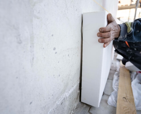 Handwerker installiert Wärmedämmung an Gebäudewand zur Energieeffizienz-Steigerung