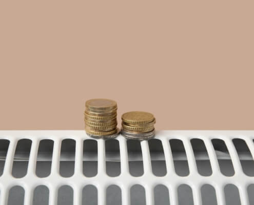 Münzen auf Heizkörper als Metapher für Kosteneffizienz und staatliche Förderung von Wärmepumpen